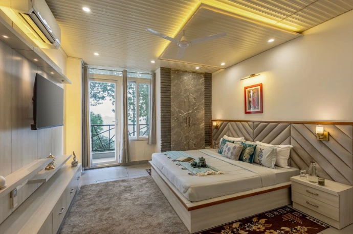 Modern standard hotel room at Serenity Suites featuring elegant interiors, comfortable double bed, warm lighting, wall-mounted TV, private balcony, and a relaxing ambiance for a restful stay